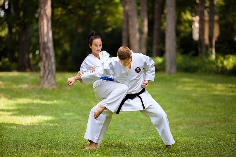 Students learning new techniques in adult martial arts class.