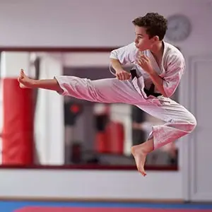 Martial arts student practicing a high kick at a dojo; ideal for kids and adult classes in Fairfield.
